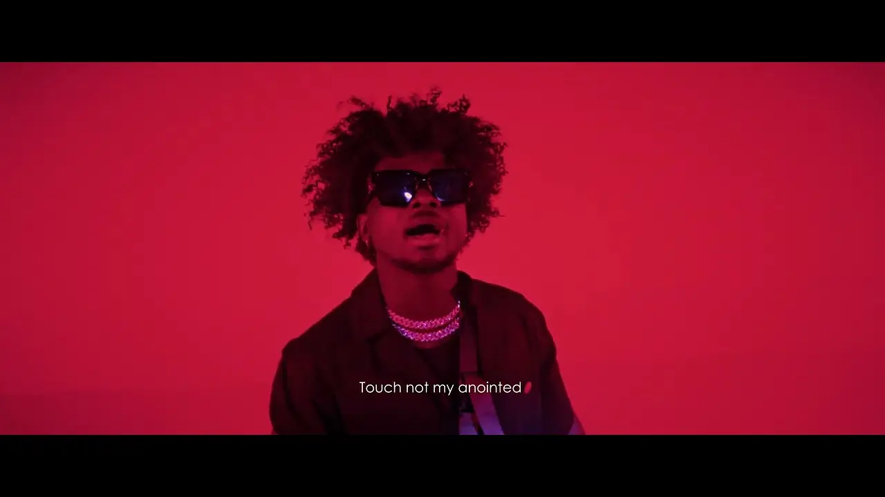 A man with curly hair wearing sunglasses and a necklace in front of a red background, with the phrase "touch not my anointed" displayed as a caption. thumbnail for the video "Kuami Eugene - Canopy (Official Visualiser) "