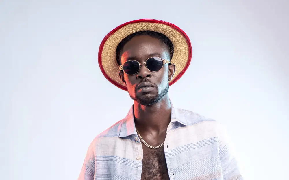 Image of Ghanaian producer and rapper, Skonti, in a white top and summer hat