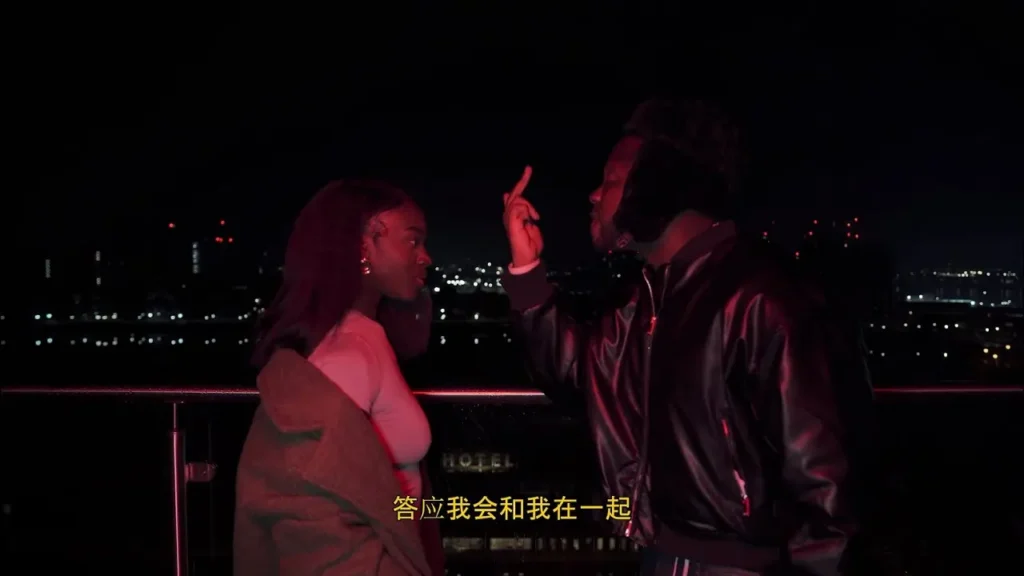 A woman and man are standing on a rooftop at night, having an intense conversation. The city skyline is illuminated in the background, reminiscent of scenes from Medikal's "Not Searching (Official Video).